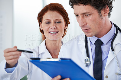 Buy stock photo Cropped shot of two doctors looking at a patient's file