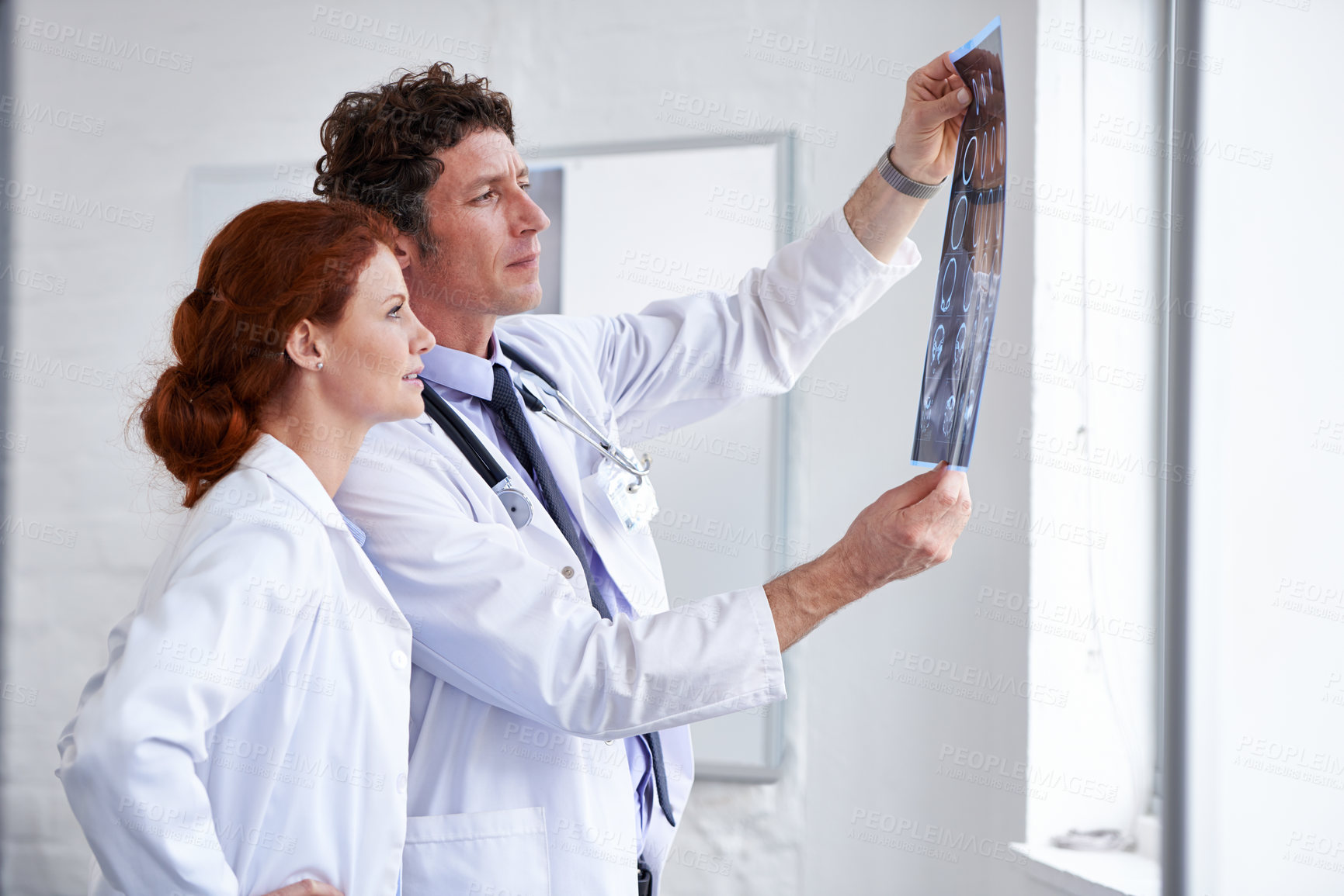 Buy stock photo Shot of two doctors assessing a patient's x-ray at the hospital