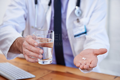 Buy stock photo Cropped shot of a male doctor holding a pill and glass of water
