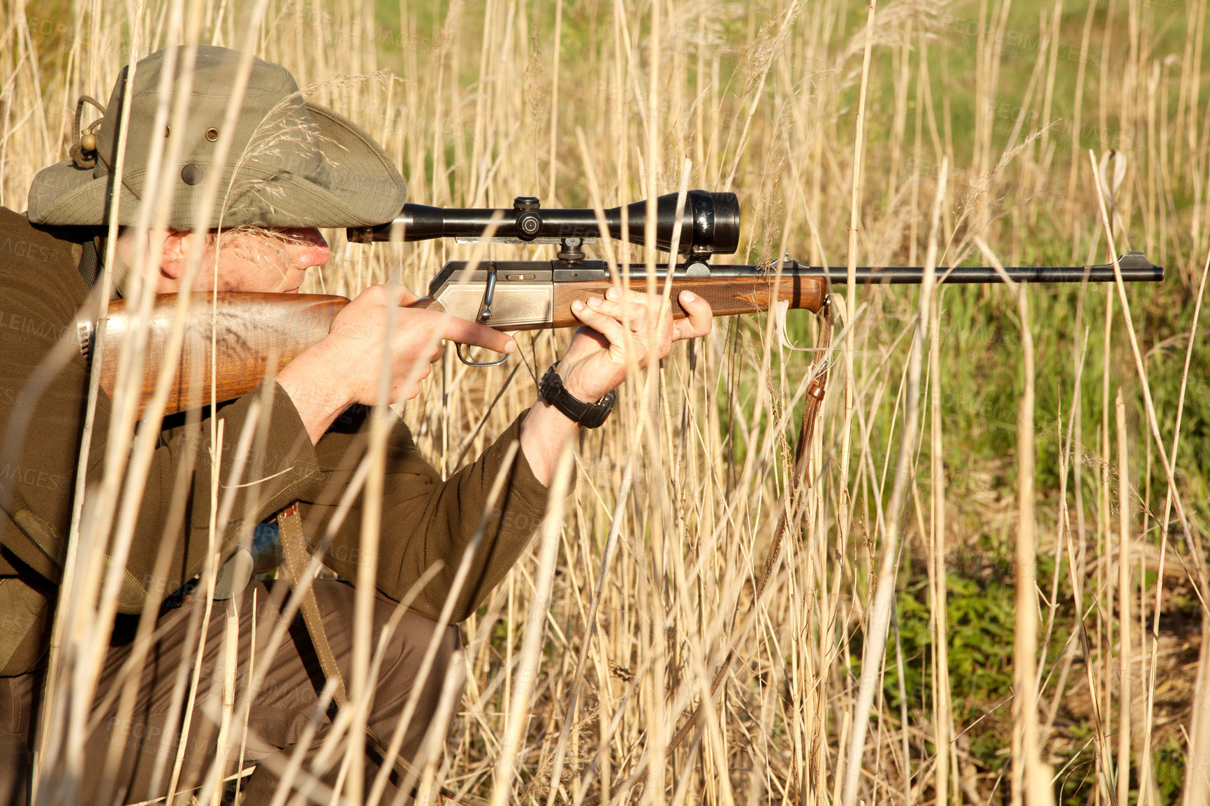 Buy stock photo Nature, wildlife and male hunter with a shotgun while in camouflage shooting in outdoor field. Grass, safari and man hunting animals with rifle weapon hiding in plants to shoot target in countryside.