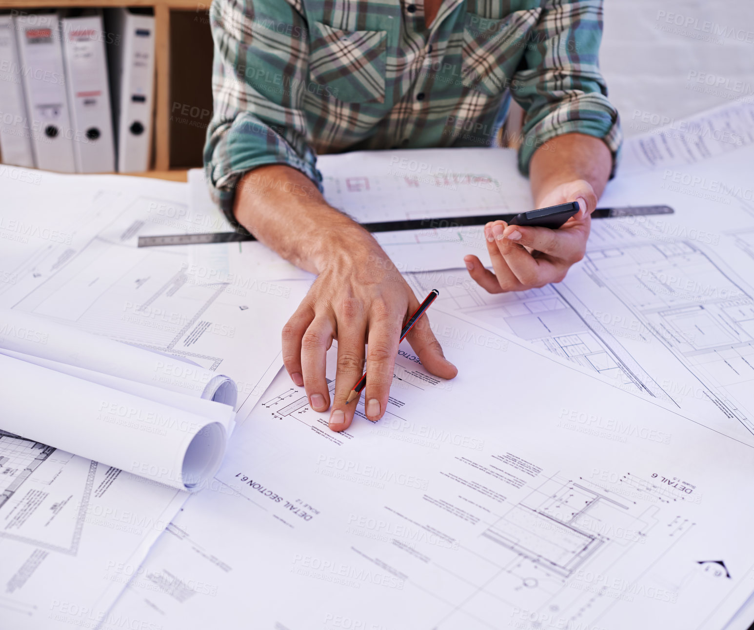 Buy stock photo Cropped shot of a male architect working on blueprints at a table