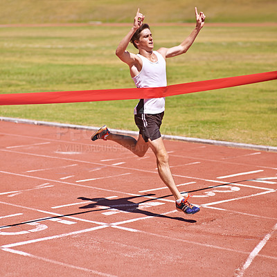 Buy stock photo Shot of a young male athlete crossing the finish line and winning the race
