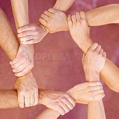 Buy stock photo Working in unity or solidarity linked together in life. Arms interlocked symbolize support for one another. Closeup overhead of a group of male hands and arms holding one another in a circle