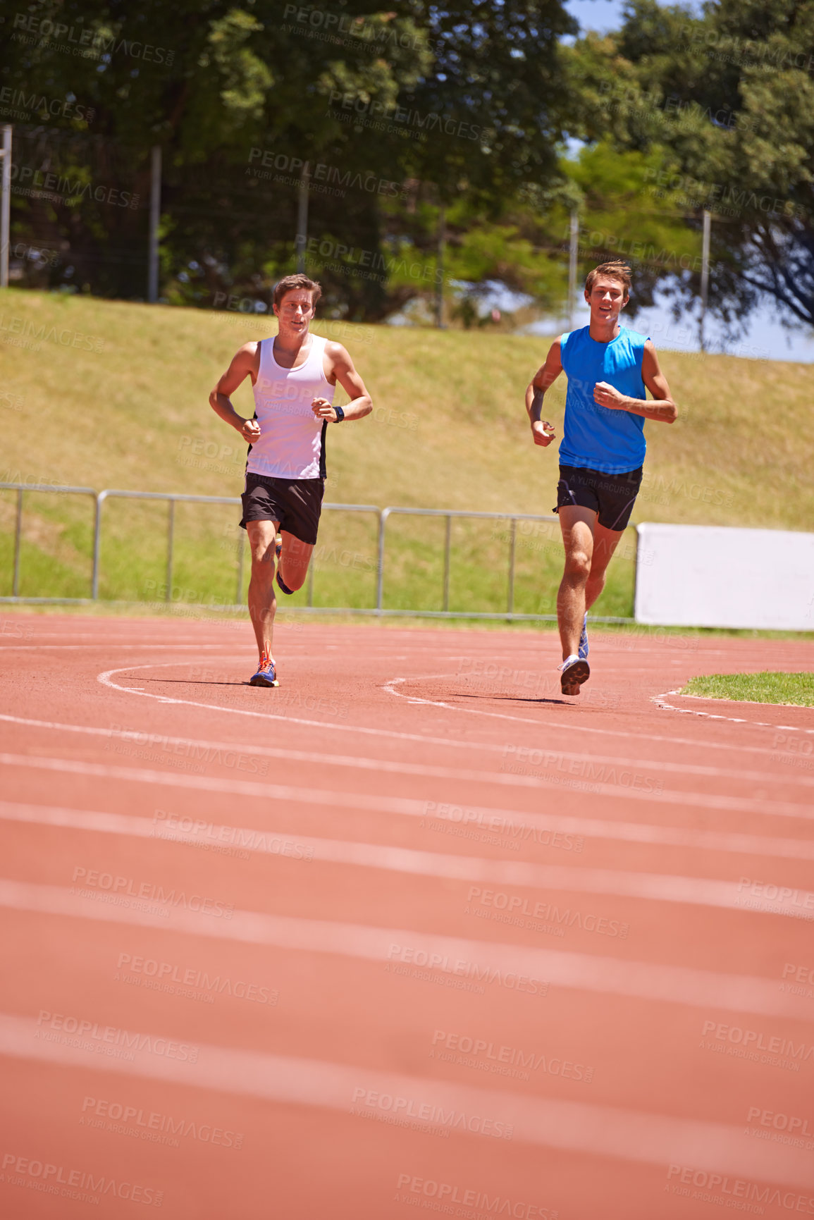 Buy stock photo Shot of two male athletes running on a track