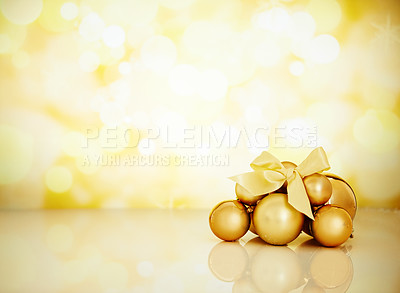 Buy stock photo Studio shot of Christmas ornaments against a gold background