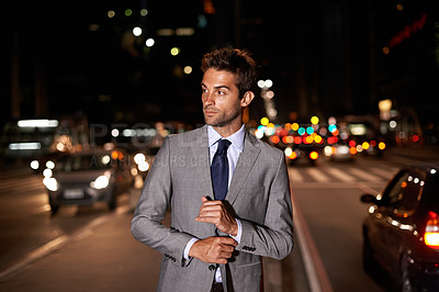 Buy stock photo A handsome businessman posing in the middle of a busy city street at night