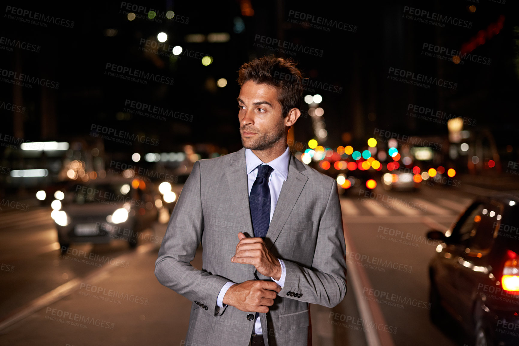Buy stock photo A handsome businessman posing in the middle of a busy city street at night