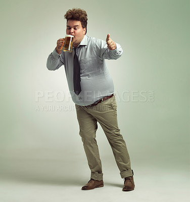 Buy stock photo Shot of an overweight man giving thumbs up while drinking a pint of beer