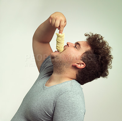 Buy stock photo Studio shot of an overweight man shoving a stack of chips down his throat