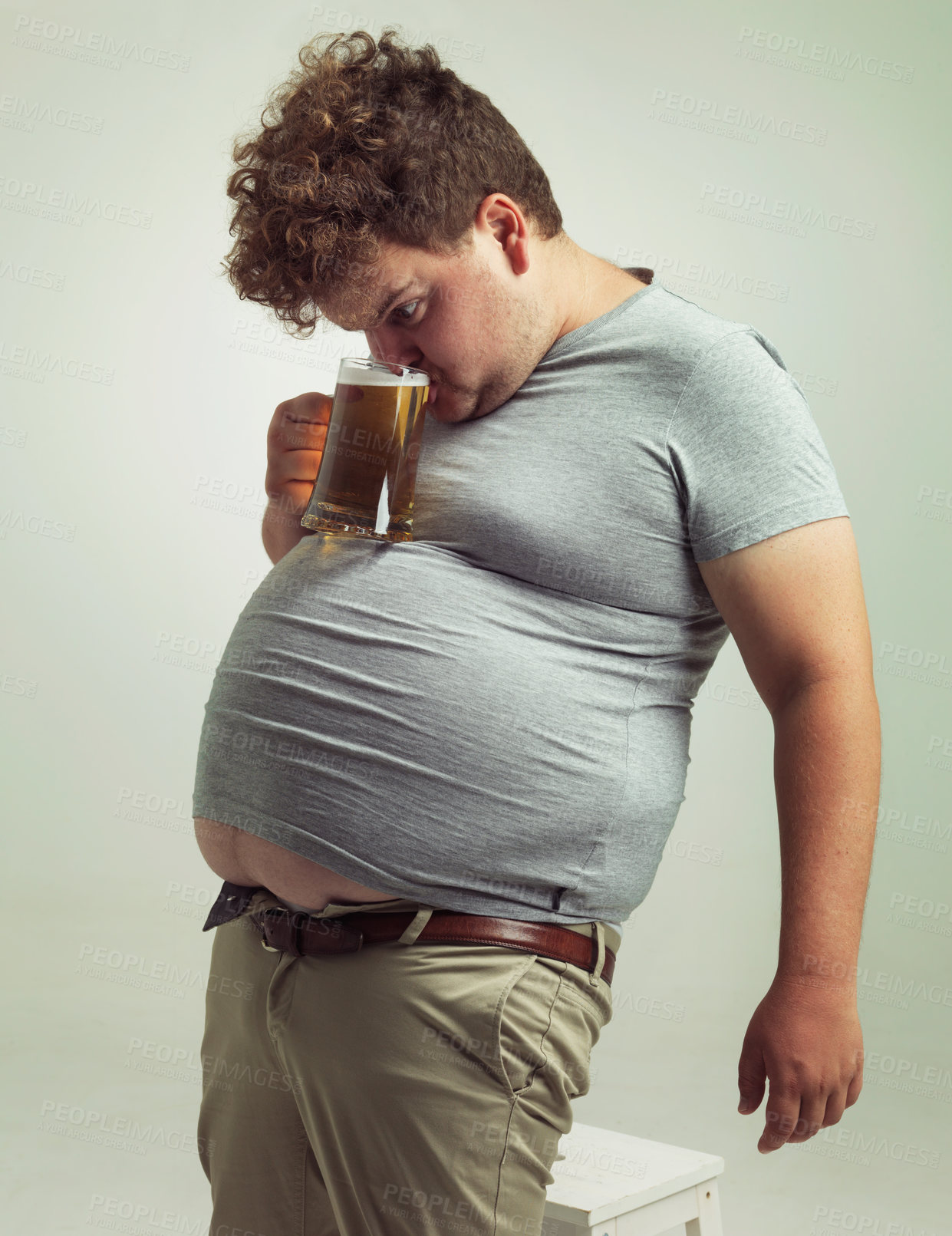 Buy stock photo Obese, weight gain and alcohol for man in studio with drink for unhealthy habit, plus size and joke. Overweight person with glass on fat stomach for balance, comedy and humor for lager and comic 