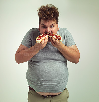 Buy stock photo Studio shot of an overweight man eating two hotdogs at once