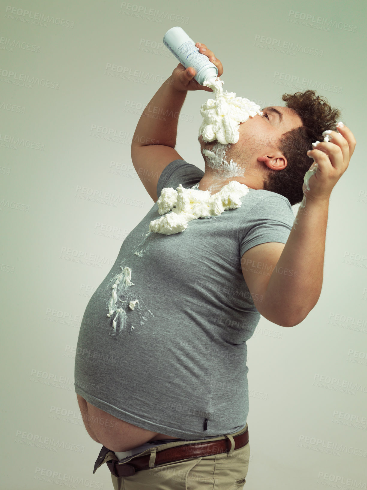 Buy stock photo Plus size, eating and man with cream in studio for unhealthy, sugar and sweet snack or dessert. Messy, greedy and hungry plus size male person enjoying whipped dairy product by gray background.