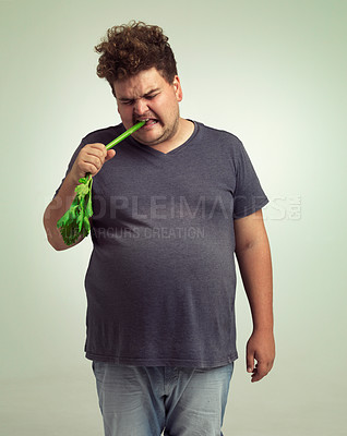 Buy stock photo Obesity, weight gain and humor for man in studio with celery for health eating, nutrition and diet. Overweight person with vegetable in mouth and cry for hungry, and  food with vitamin for comic 