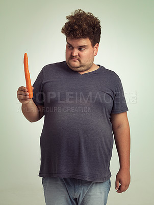 Buy stock photo Man, vegetables and carrot in studio with thinking for healthy snack, detox and vitamin c for wellness. Plus size, male person and unhappy with organic food for nutrition, lifestyle and diet