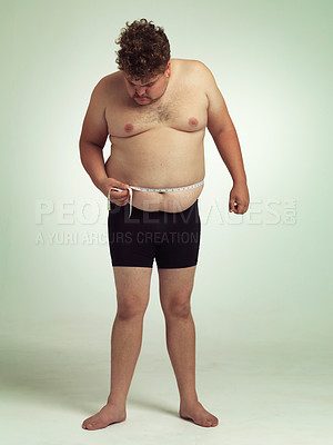 Buy stock photo Man, plus size and tape for measurement in studio on white background for body, progress and weight loss. Looking down, negative and stomach with self care to monitor health and shape to exercise