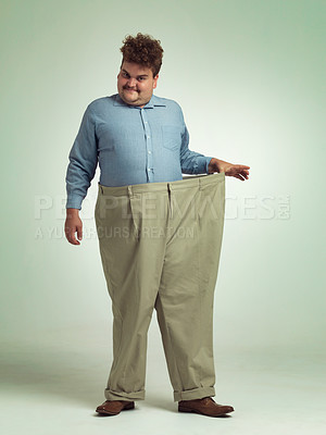 Buy stock photo Happy man, portrait and plus size with pants for weight loss, measurement or waist on a studio background. Male person with smile for healthy diet, obesity or overweight clothing on mockup space