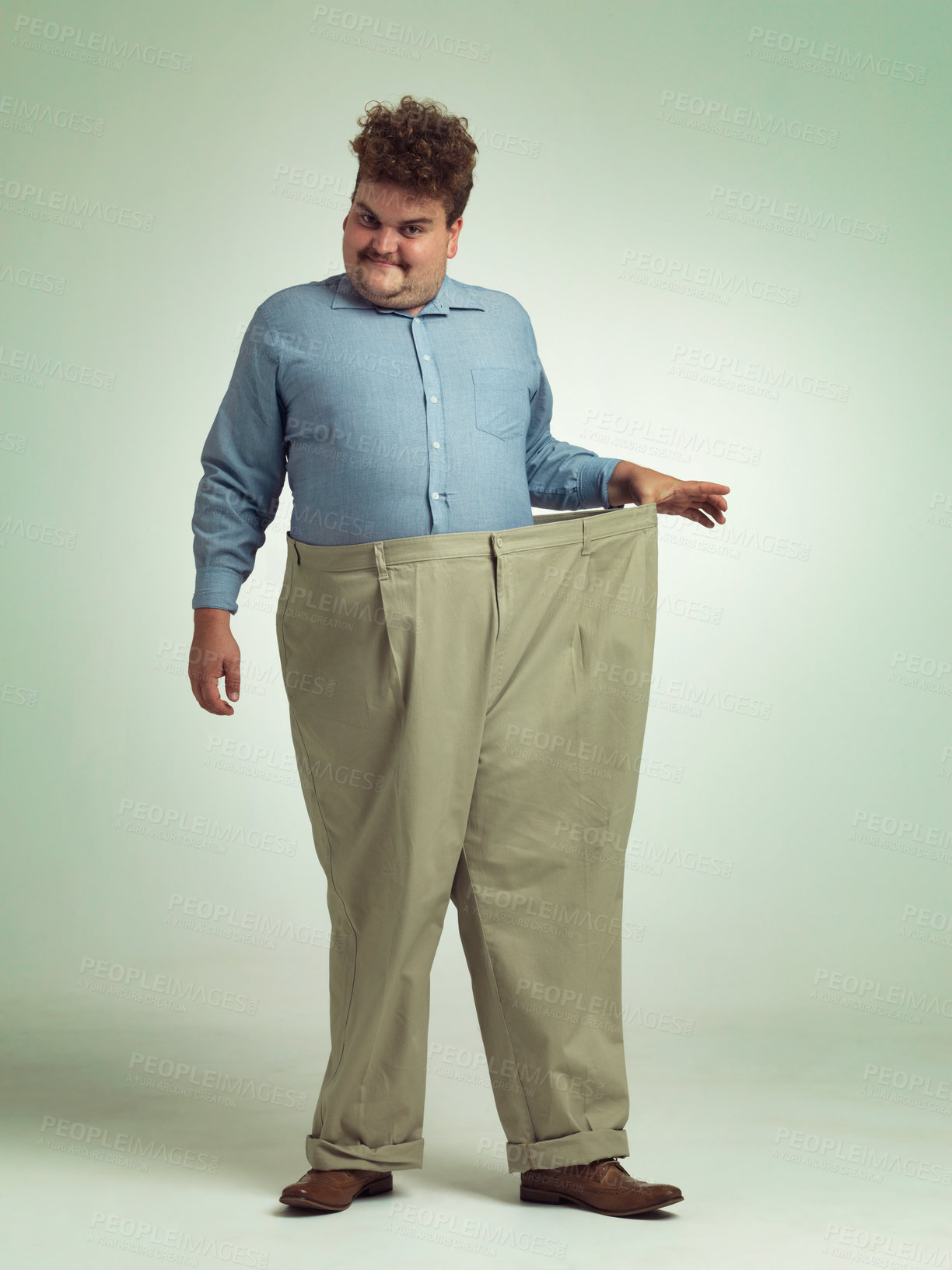 Buy stock photo Happy man, portrait and plus size with pants for weight loss, measurement or waist on a studio background. Male person with smile for healthy diet, obesity or overweight clothing on mockup space