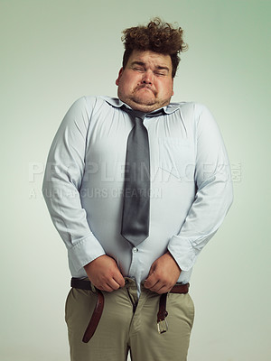 Buy stock photo Man, pants and plus size with big waist in obesity, overweigh or measurement on a studio background. Young male person struggling to fit on clothing with body fat or chubby stomach on mockup space