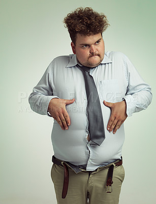 Buy stock photo Man, stomach and plus size with belly from unhealthy diet or weight gain on a studio background. Young male person or big guy holding tummy for eating disorder or body conscious on mockup space