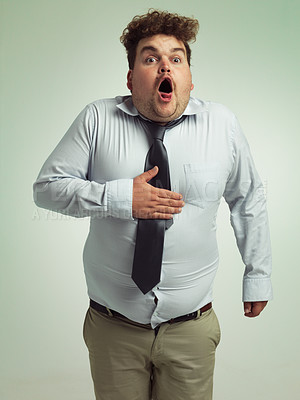 Buy stock photo Shot of an overweight man holding his chest