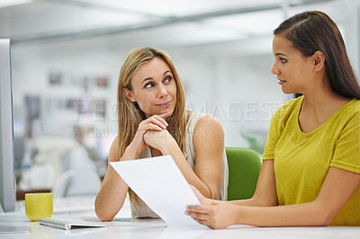 Buy stock photo Two attractive female colleagues going over some documents at work