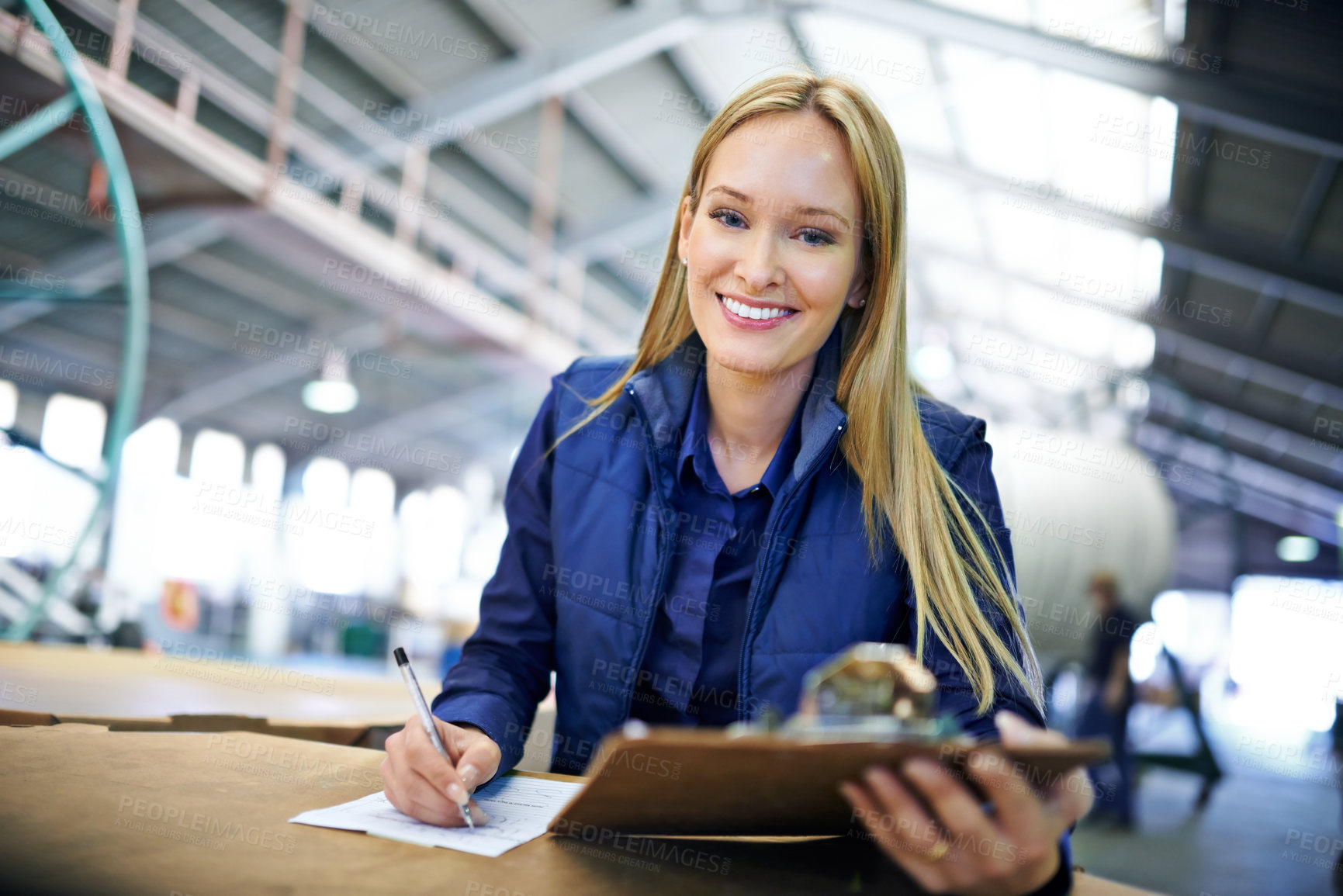 Buy stock photo Woman, supervisor and writing with clipboard in logistics at factory with machines for supply chain. Portrait, warehouse and paperwork on table in manufacturing and distribution business with smile