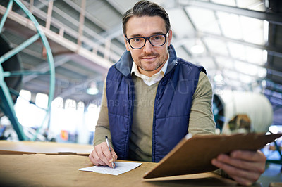 Buy stock photo Man, manager and writing with clipboard in logistics at factory with machines for supply chain. Portrait, warehouse and paperwork on table at manufacturing and distribution business with smile