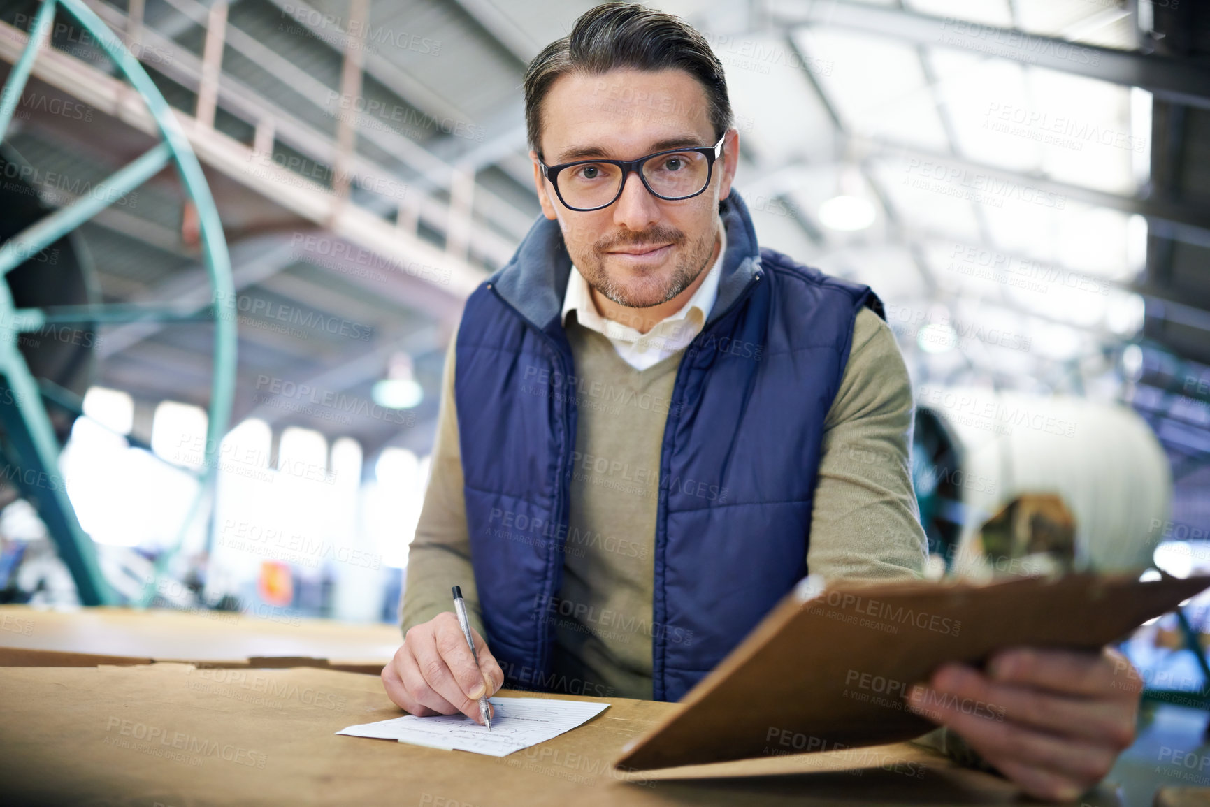 Buy stock photo Man, manager and writing with clipboard in logistics at factory with machines for supply chain. Portrait, warehouse and paperwork on table at manufacturing and distribution business with smile