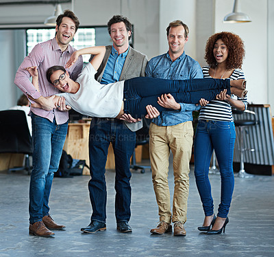 Buy stock photo Colleagues having fun, playing and feeling playful while carrying fun coworker, being silly and goofy in office together. Portrait of diverse group or team of smiling creative business men and women