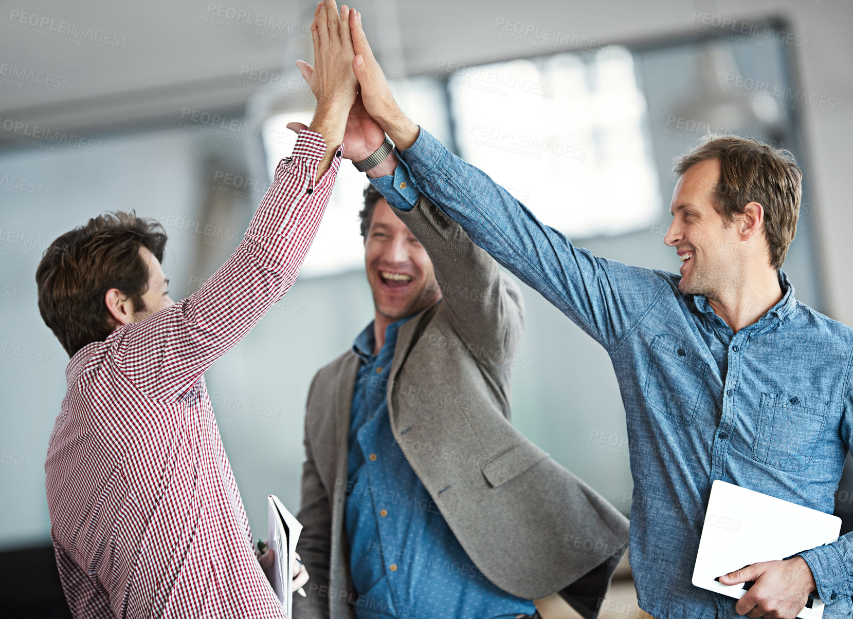 Buy stock photo Excited, cheerful and happy group of male business people high fiving for motivation in an office. Group of professional work colleagues show support and celebrating after a team building meeting.