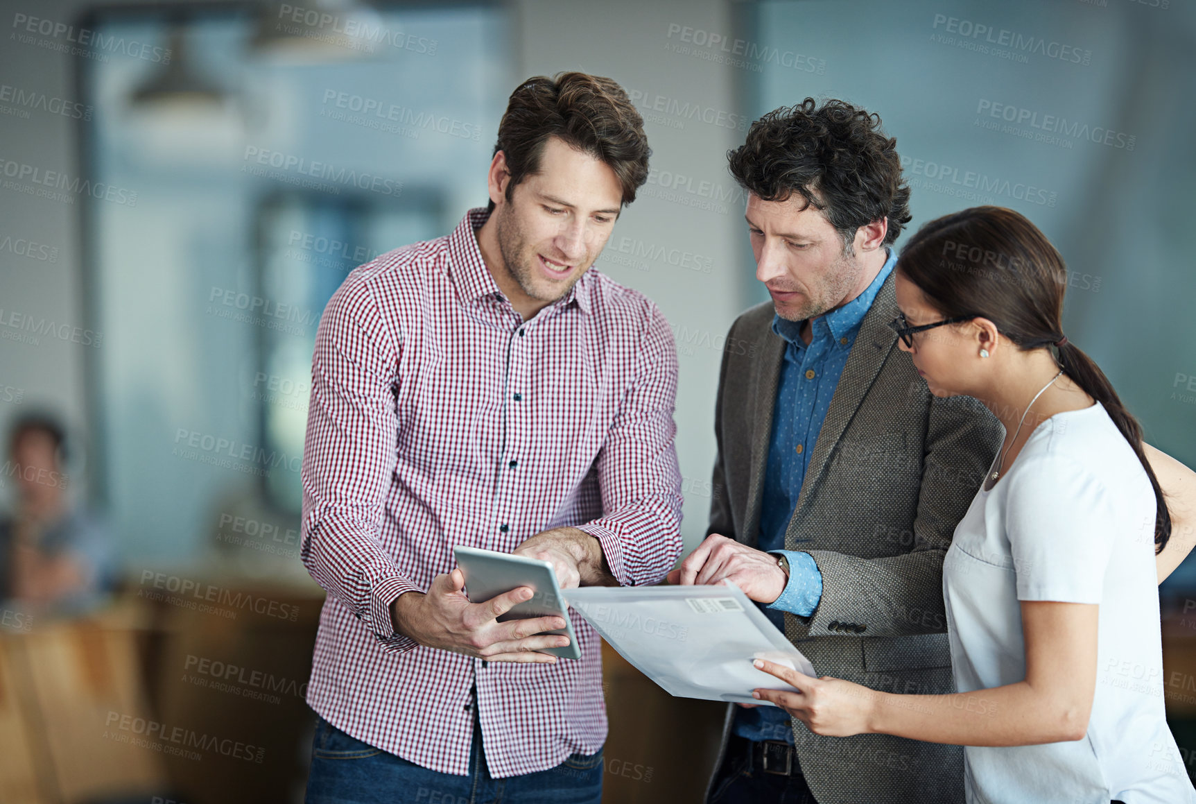 Buy stock photo Shot of a group of coworkers standing in an office talking over a digital tablet