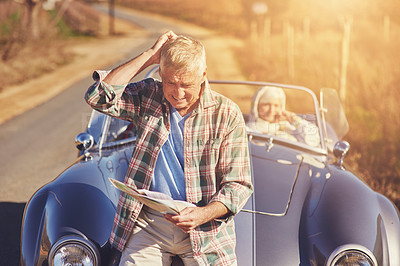 Buy stock photo Shot of a senior man looking at a map while on a roadtrip with his wife