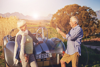 Buy stock photo Senior couple, phone and photo in countryside with sunny for summer vacation, car trip and camera pose. Mature people, mobile and picture with transport for retirement, journey and together in France