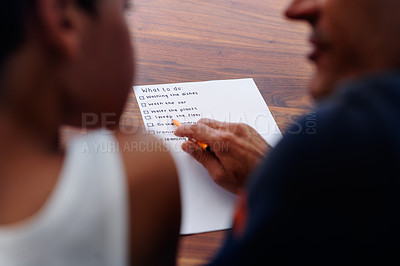 Buy stock photo Rear view shot of a father going over a list of chores with his son at home