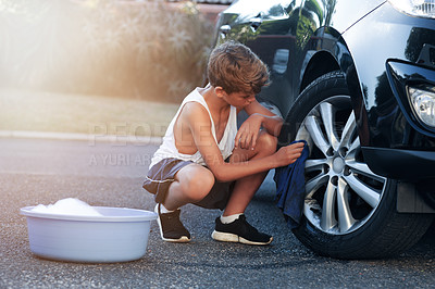 Buy stock photo Shot of a young boy washing the wheel of a car