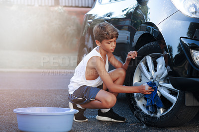 Buy stock photo Shot of a young boy washing the wheel of a car