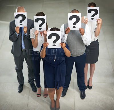 Buy stock photo High angle shot of a group of businesspeople holding questions marks in front of their faces
