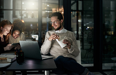 Buy stock photo Night business, man and eating noodles in office for laptop, planning or research in startup. Young employee, fast food and computer overtime in dark agency with happy team, productivity or deadlines