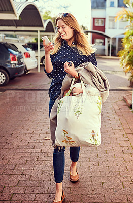 Buy stock photo Shot of an attractive young woman texting on her cellphone while out in the city