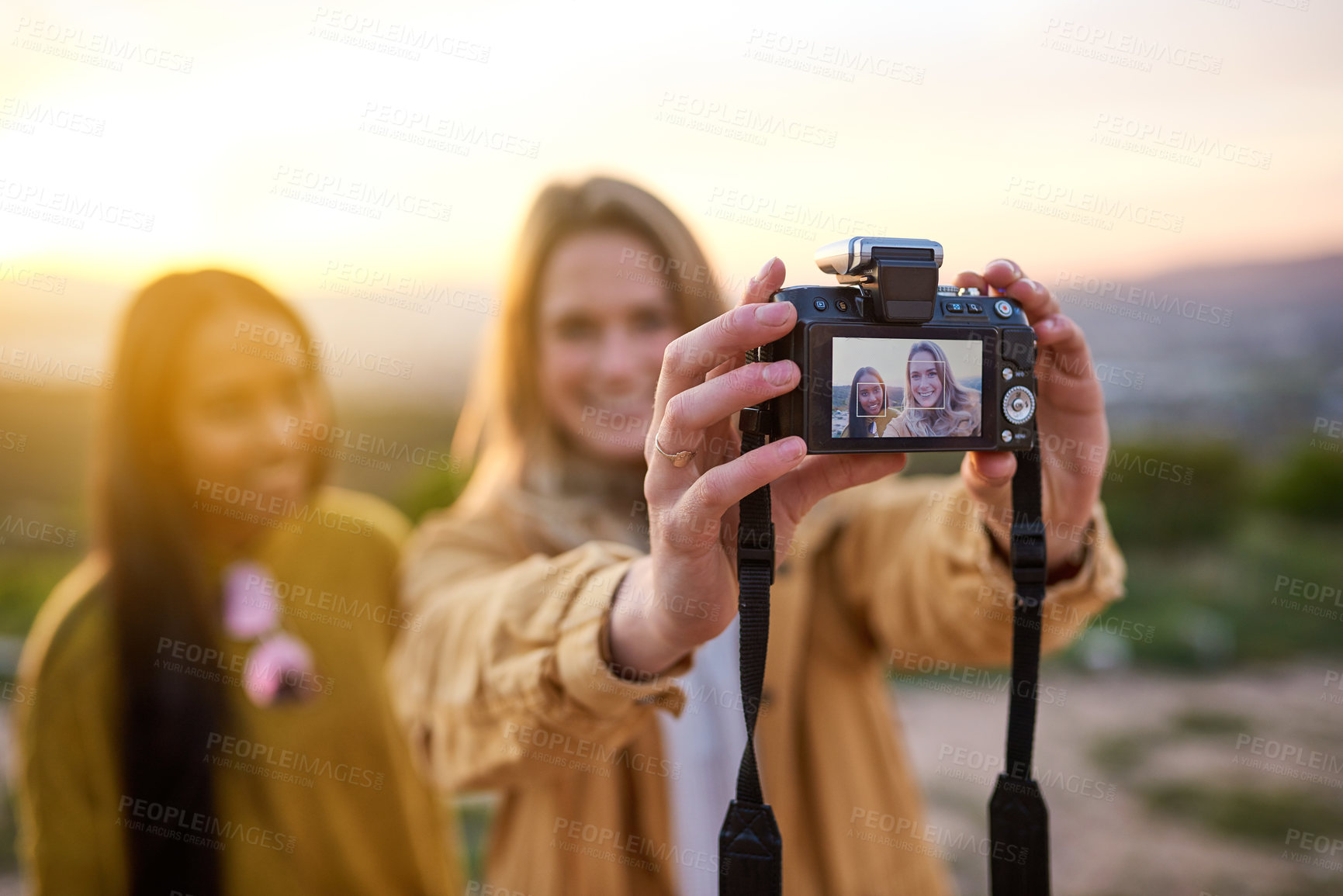 Buy stock photo Shot of two friends taking a selfie with a digital camera while standing outside