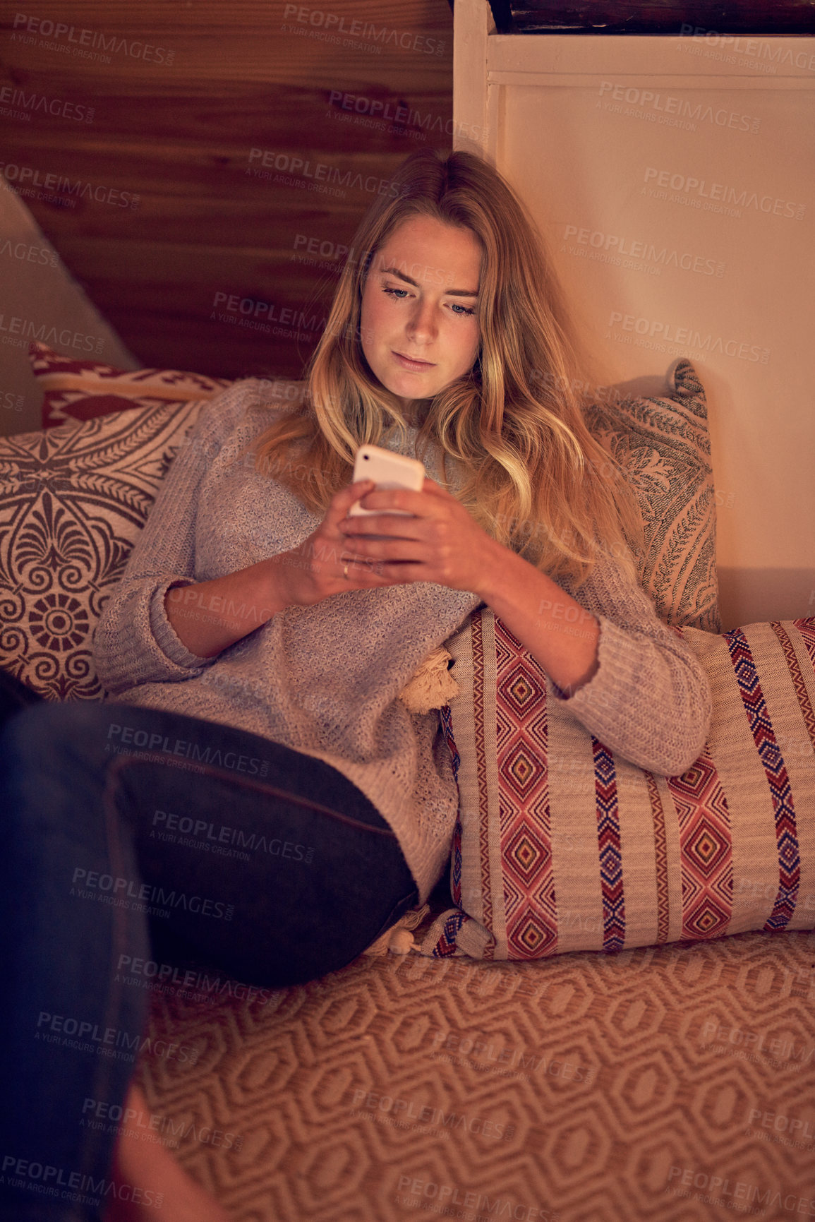 Buy stock photo Shot of a young woman texting on her smartphone while relaxing in her bedroom at home
