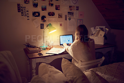 Buy stock photo Rearview shot of a young woman using her laptop in her bedroom at night
