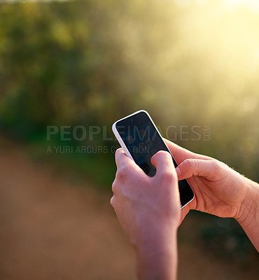 Buy stock photo Shot of an unidentifiable woman sending a text message while in a park