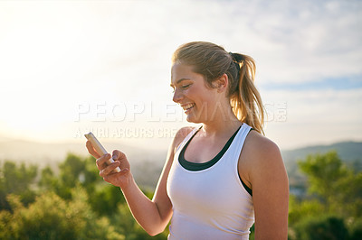 Buy stock photo Shot of an attractive young woman using her phone while exercising outdoors