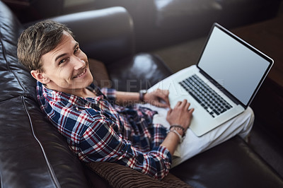 Buy stock photo High angle portrait of a handsome young man using his laptop while sitting on the sofa at home