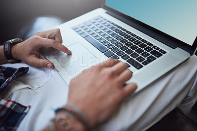 Buy stock photo High angle shot of an unrecognizable man using his laptop while sitting on the sofa at home