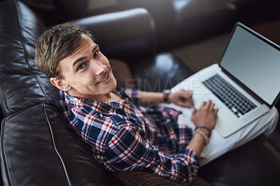 Buy stock photo High angle portrait of a handsome young man using his laptop while sitting on the sofa at home