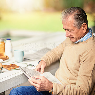 Buy stock photo Cropped shot of a senior man reading a newspaper with his breakfast outdoors