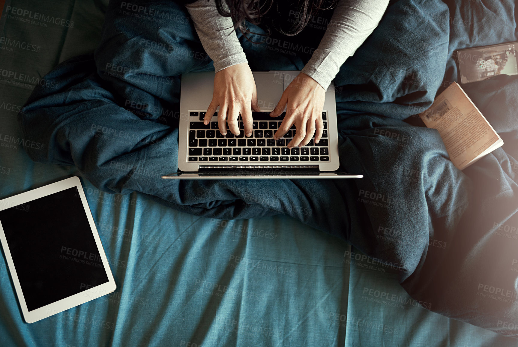 Buy stock photo High angle shot of an unidentifiable woman using her laptop while sitting in bed