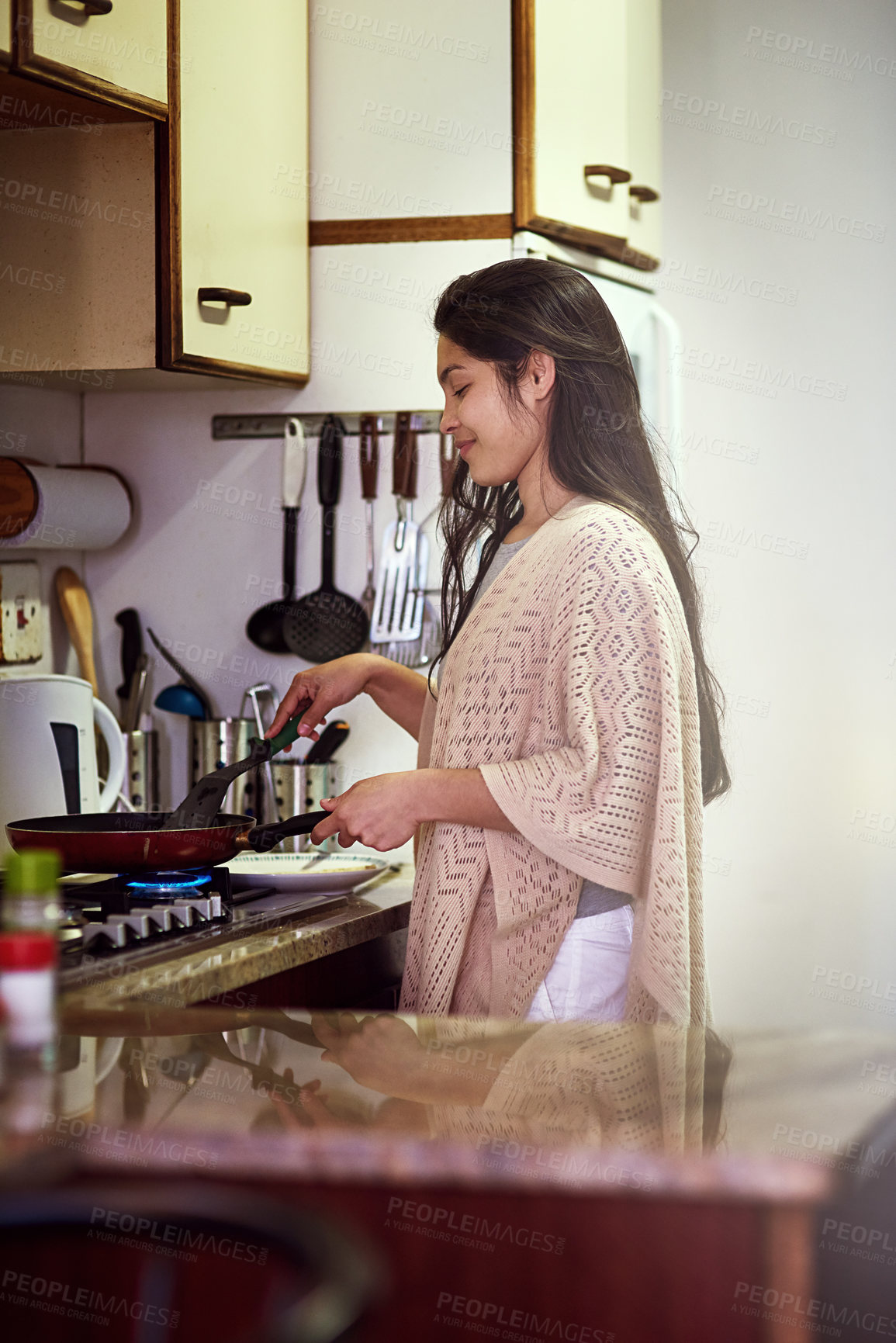 Buy stock photo Shot of a happy young woman cooking breakfast in her kitchen at home